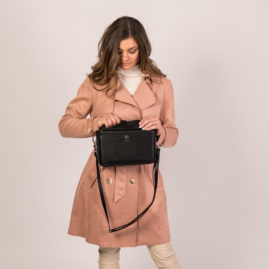 Eine junge Frau schaut in die geöffnete Crossbody ZOE XL in schwarz und silber