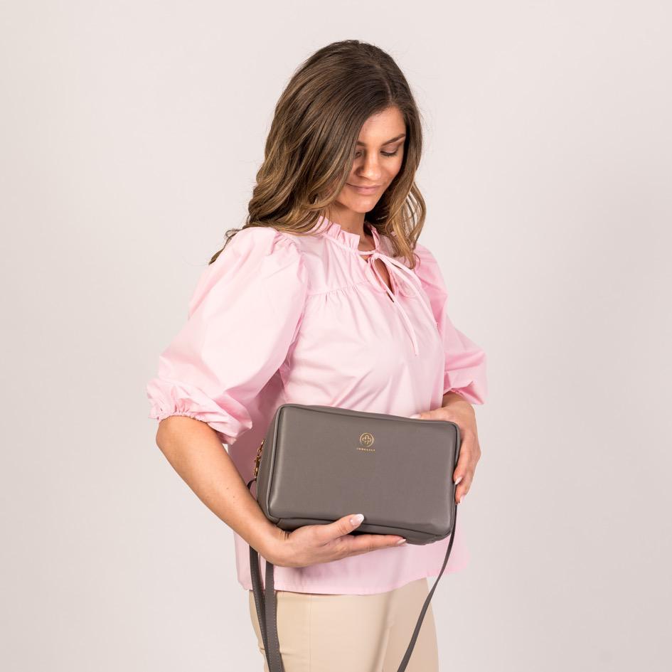 Ein Model trägt die Crossbody ZOE XL in graphite in der Hand und schaut von oben auf sie herab