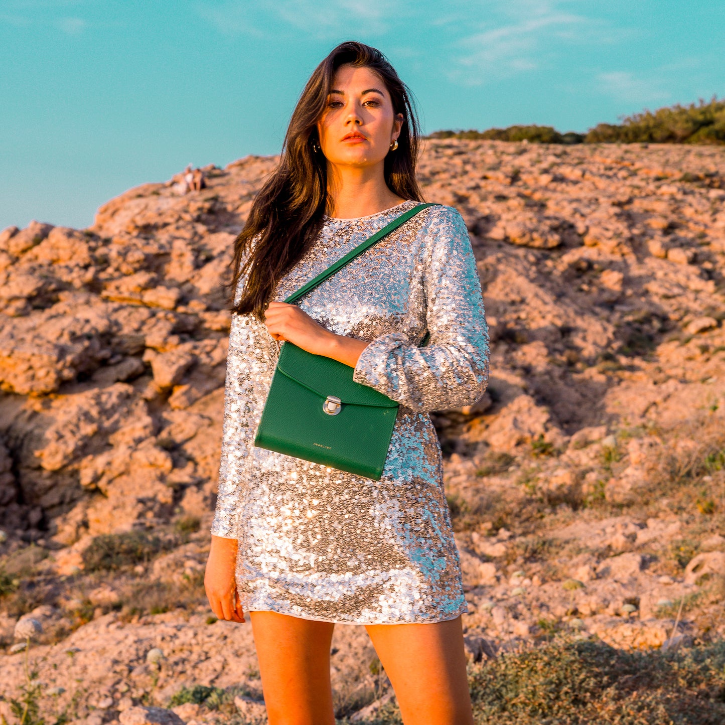 Das Model trägt ein Glitzerkleid trägt die Tasche über die Schulter.