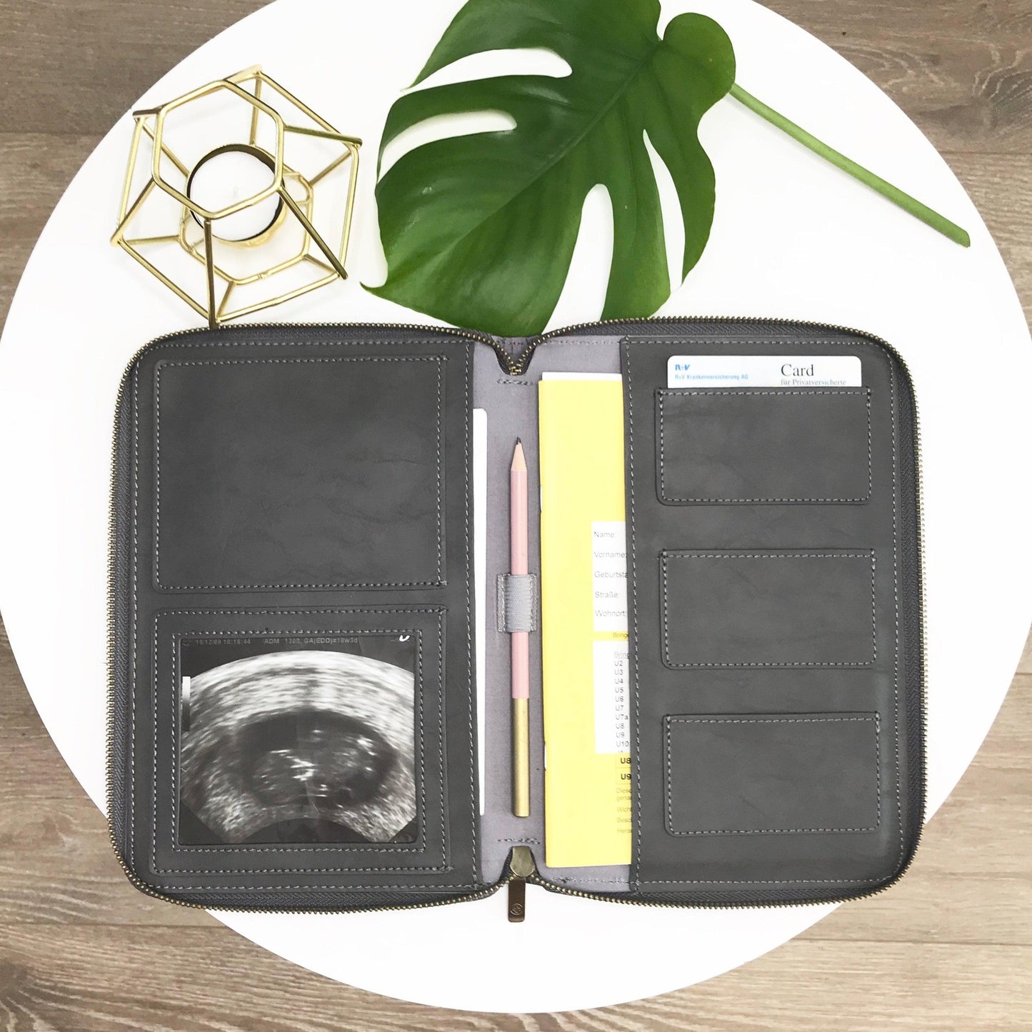 In der aufgeklappten Wallet findet man ein Ultraschallbild, einen Stift, eine Krankenkassenkarte sowie ein Untersuchungsheft