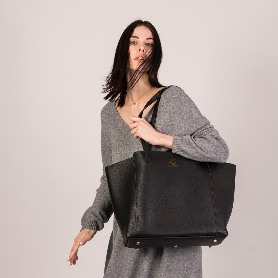 Der Shopper in schwarz wird zu einem Outfit in grau über der Schulter getragen