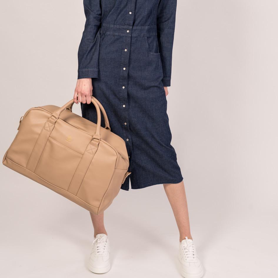 Der Linus in sand wird an den Griffen in einer Hand getragen