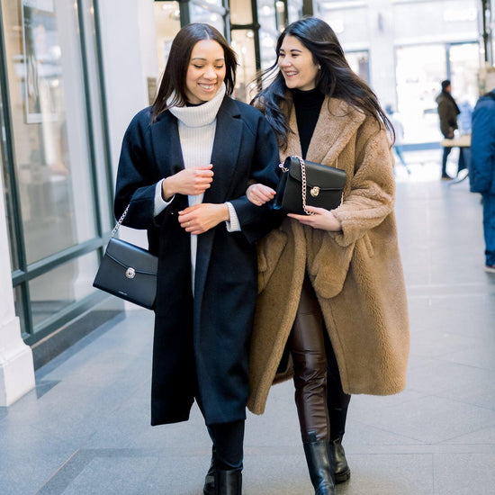 Zwei junge Frauen schlendern in einer Einkaufspassage und beide tragen die Day & Night 2.0 in schwarz und schwarz/silber