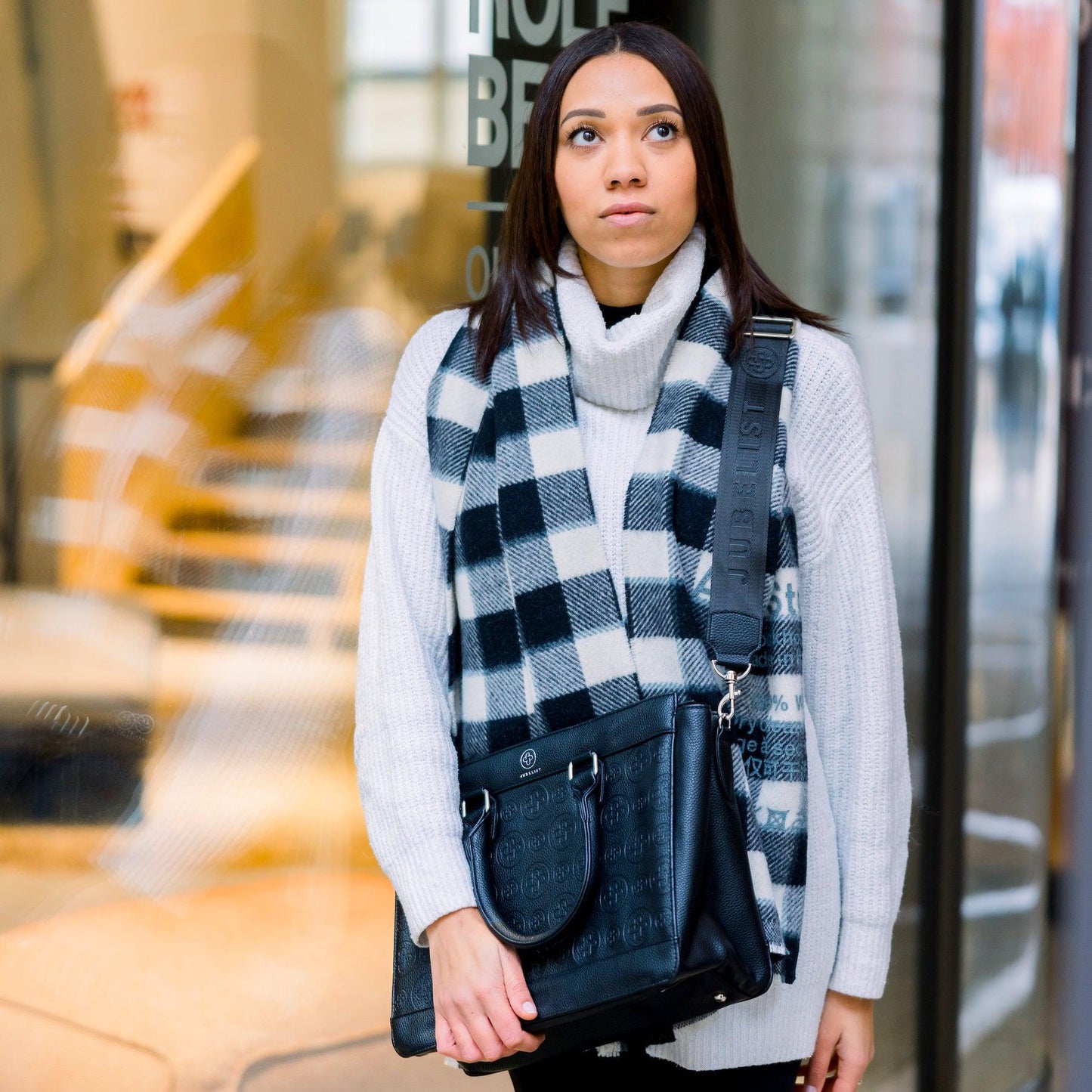 Eine junge Frau trägt die Business Bag Logo Edition in schwarz und silber crossbody mit dem Signatur Strap 