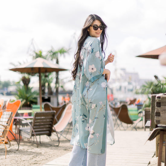 Eine junge Frau trägt den Kimono zu einer Jeans und Top und dazu eine Sonnenbrille