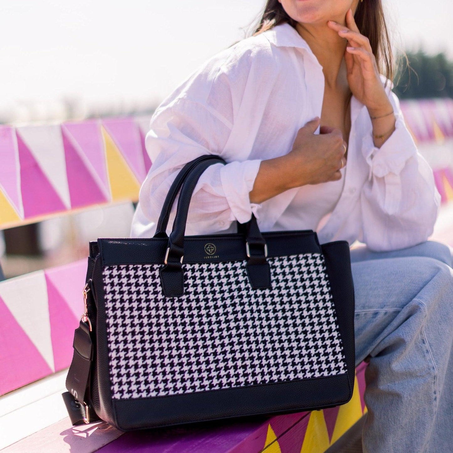 Die Business Bag Edition in black and white steht auf einer bunten Bank in Pinktönen