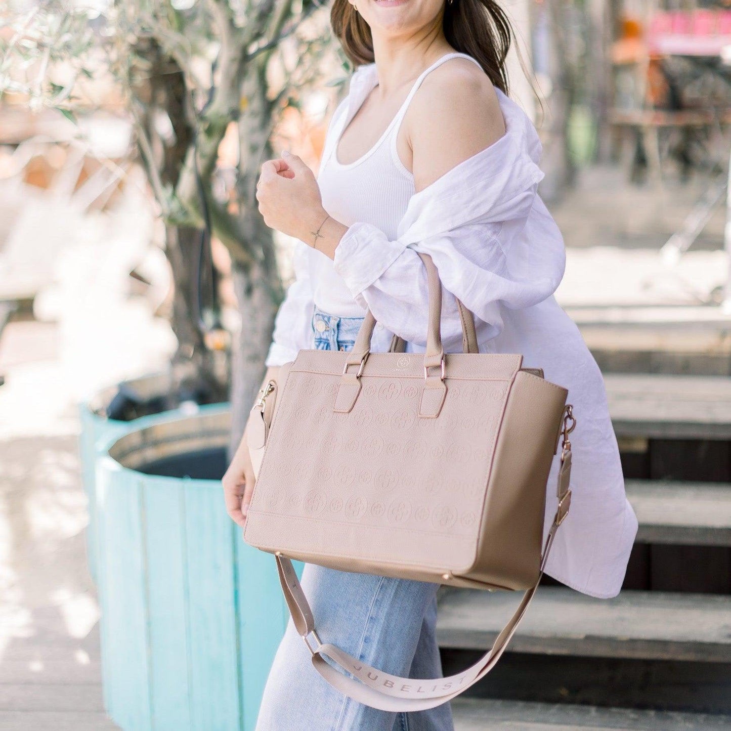 Eine junge Frau trägt die Business Bag Logo Edition in taupe lässig über den Unterarm