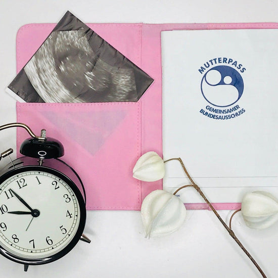 Eine aufgeklappt Canvas Mutterpasshülle in rosa zeigt eine Innentasche mit einem Ultraschallfoto und auf der anderen Seite befindet sich der Mutterpass