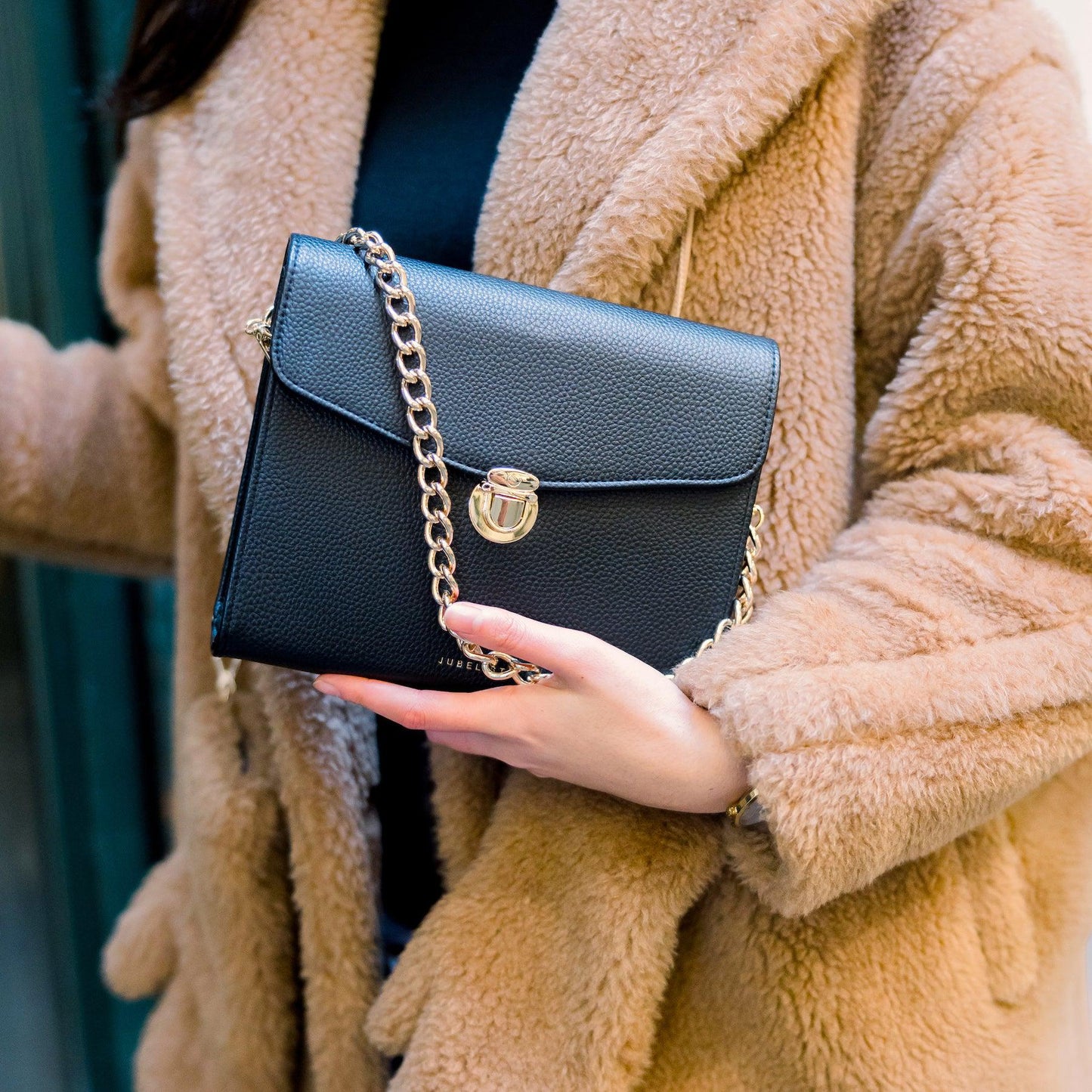 Die Tasche als Nahaufnahme wird in der Hand getragen und die Kette ist halb über die Tasche gelegt