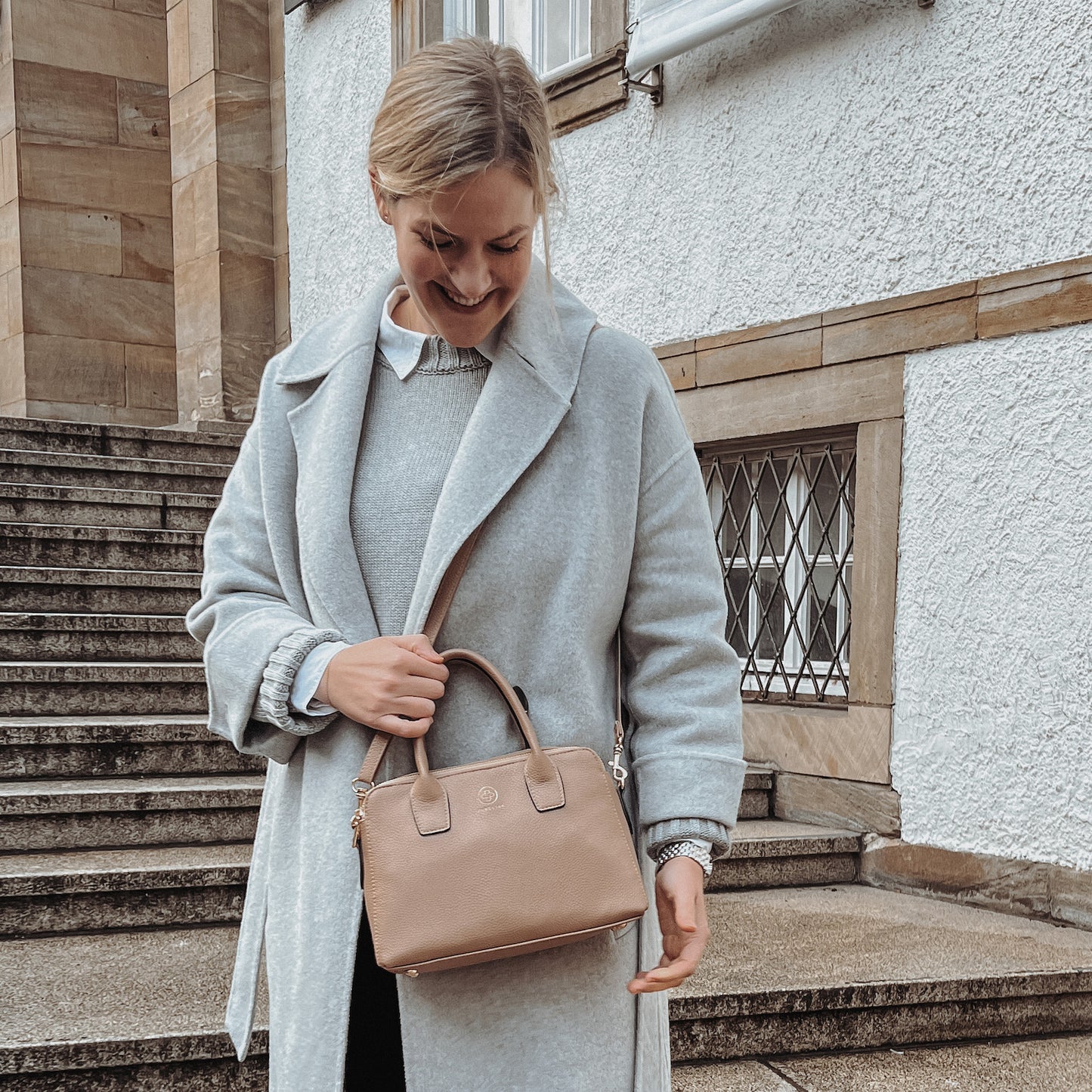 Tina Ruthe trägt ihre Emili in taupe über der Schulter  und schaut auf sie lächelnd hinunter