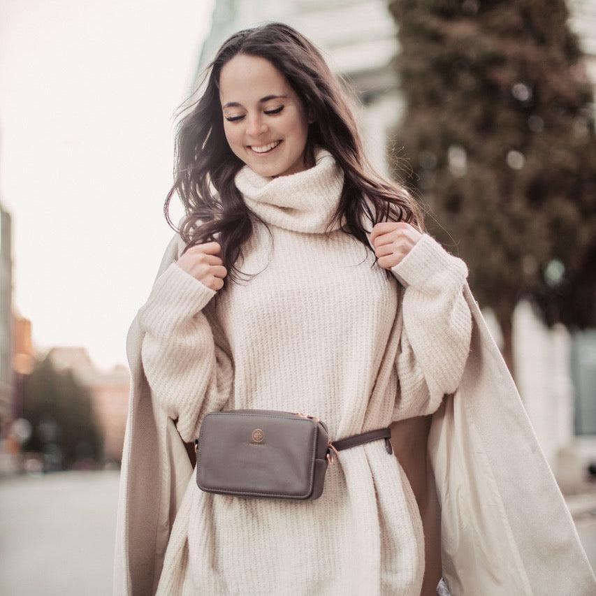 Die Jade in graphite wird als Bauchtasche zu einem weißen Rollkragenpullover getragen