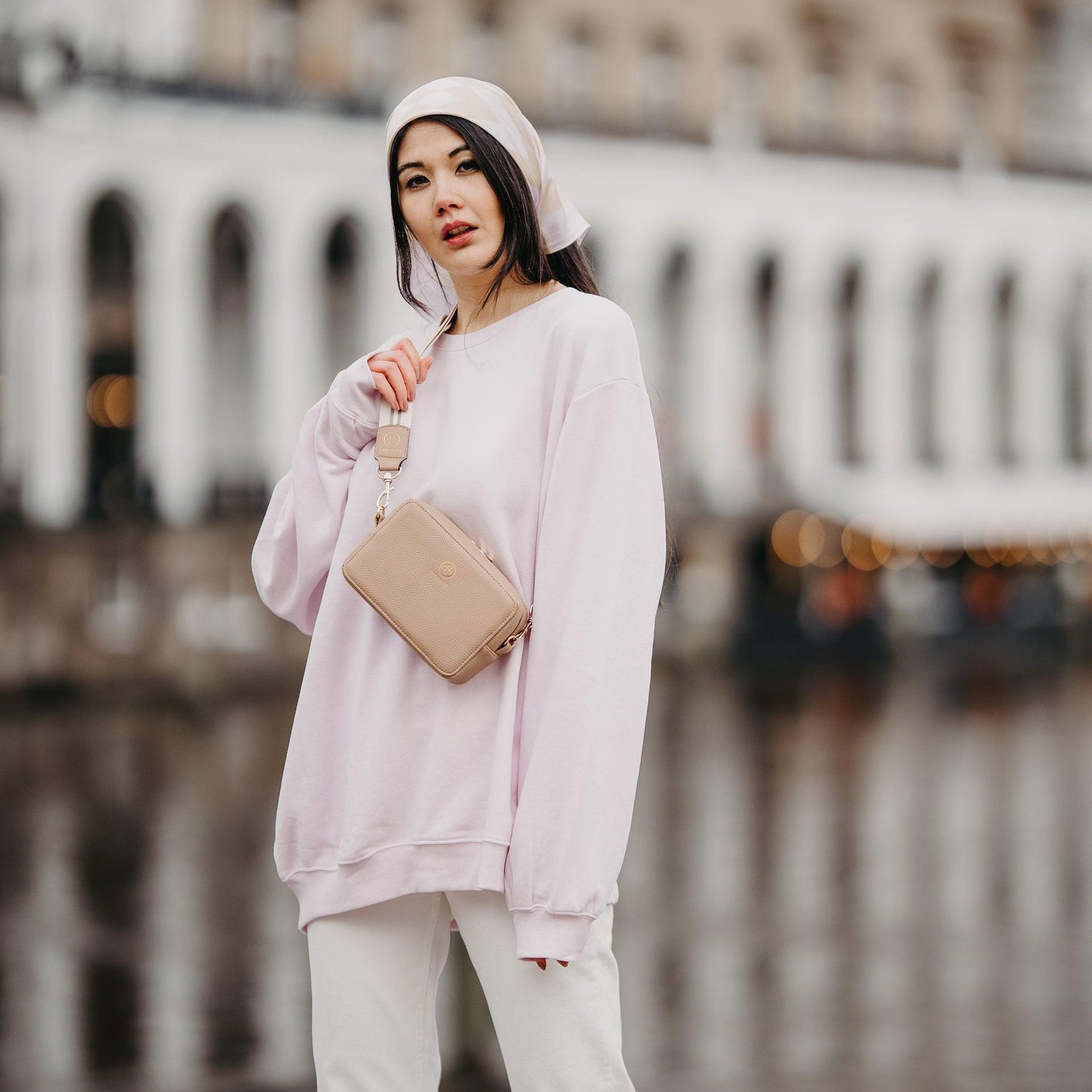 Eine junge Frau trägt die Jade mit dem Universal Strap in beige weiß crossbody nach vorne