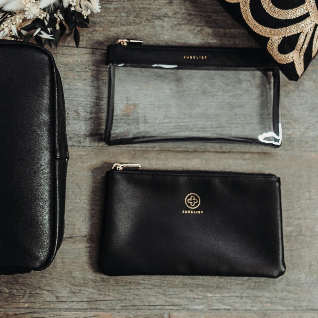 Das Pouch Set in schwarz liegt auf einem Holztisch und daneben befindet sich die Beauty Bag in schwarz