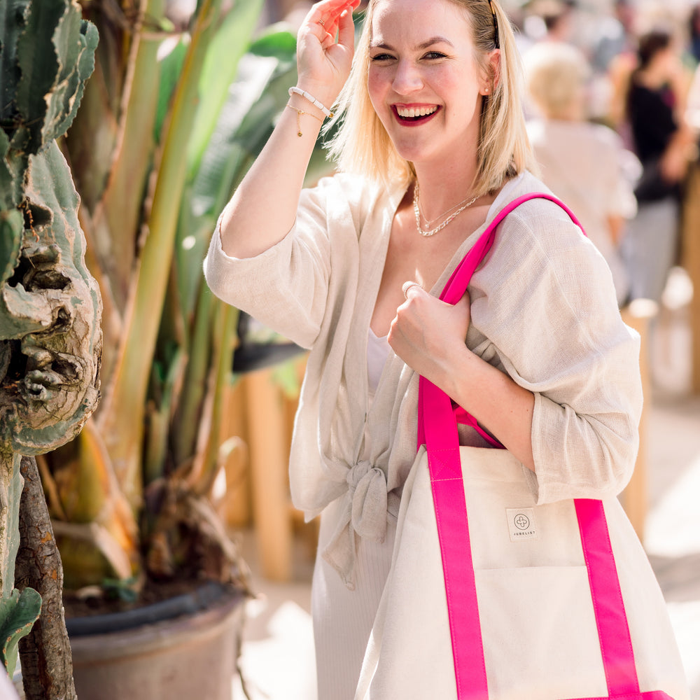 
                  
                    Tina Ruthe steht mit der pink farbenden Canvas Bag vor einem trübseligen Markt im Hintergrund.
                  
                