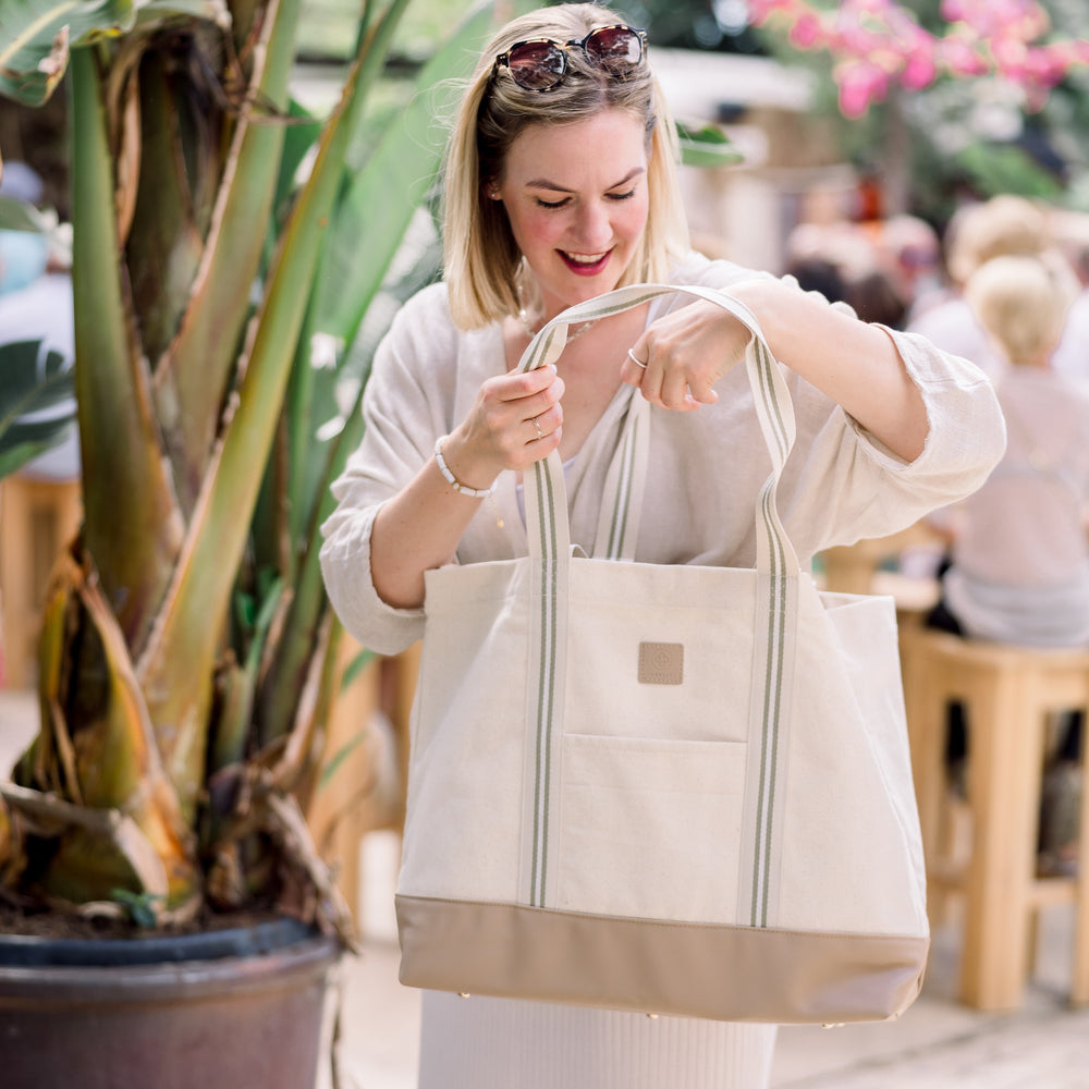 
                  
                    Tina Ruthe schaut in die sandfarbende Canvas Bag.
                  
                