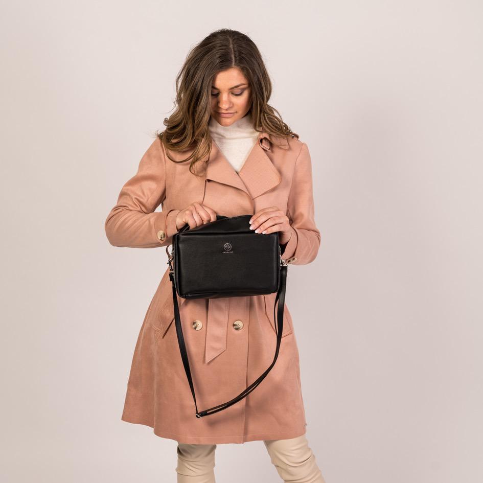 
                  
                    Eine junge Frau schaut in die geöffnete Crossbody ZOE XL in schwarz und silber
                  
                