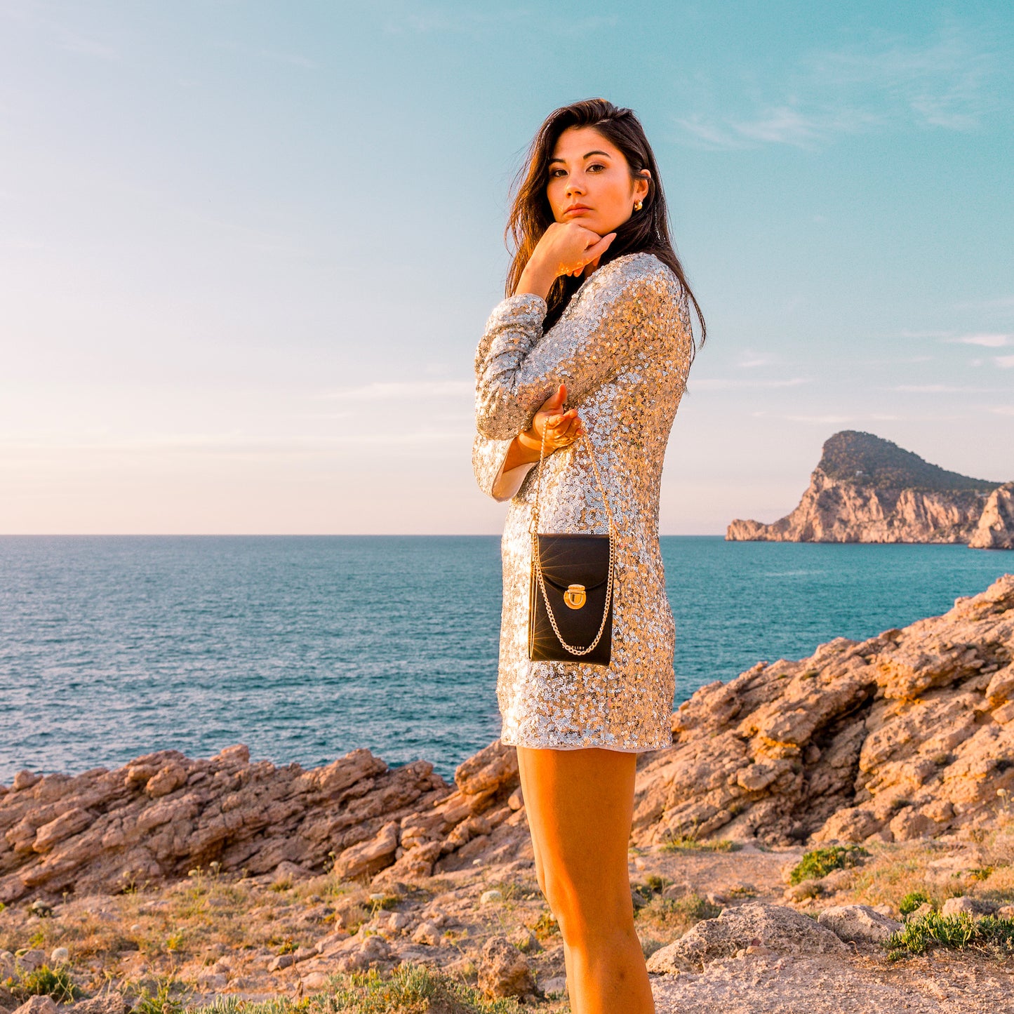 Frau in einem Glitzerkleid trägt die Day & Night mit weitem Hintergrund zum Ozean