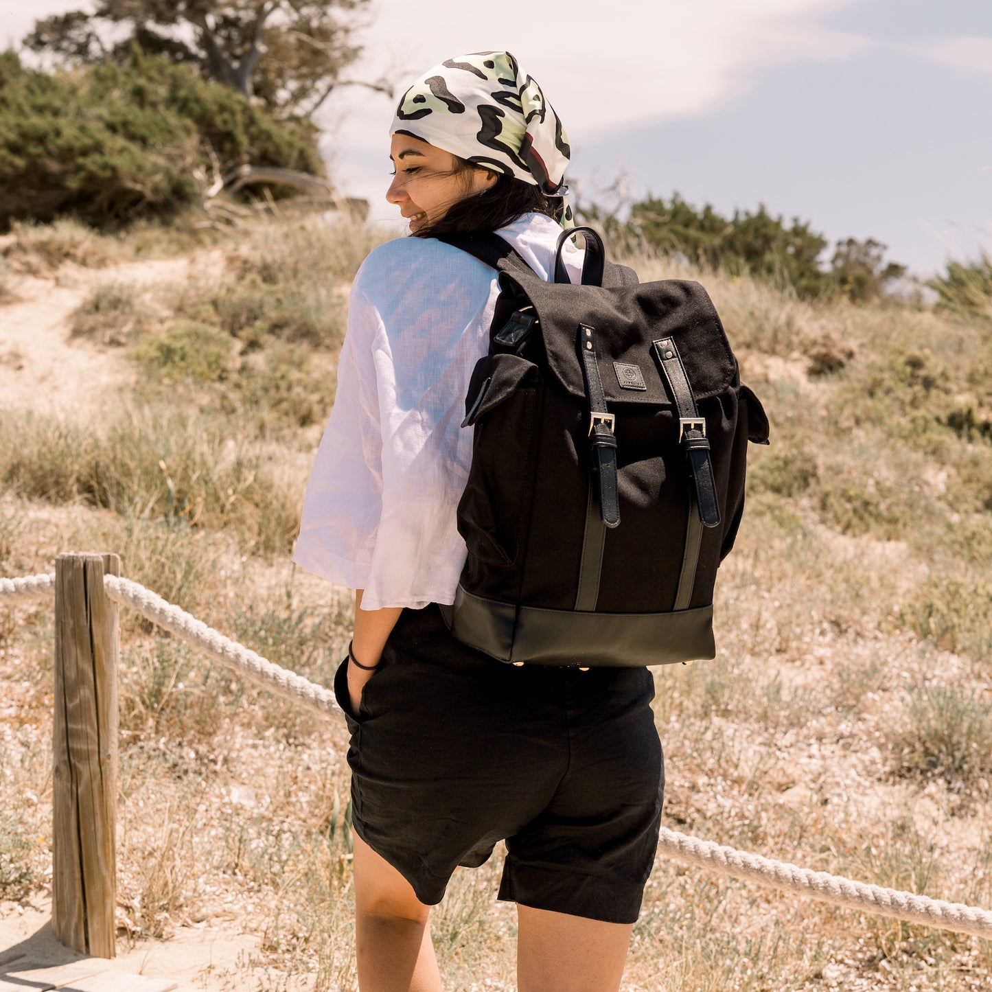 Das Model geht die Stufen an Dünen hoch, sie trägt den schwarzen Rucksack.