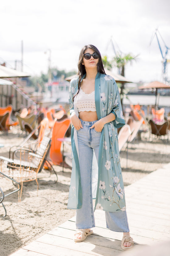 Ein Model trägt zu ihrer hellblauen Jeans und einem cremefarbenen Stricktop  den Kimono