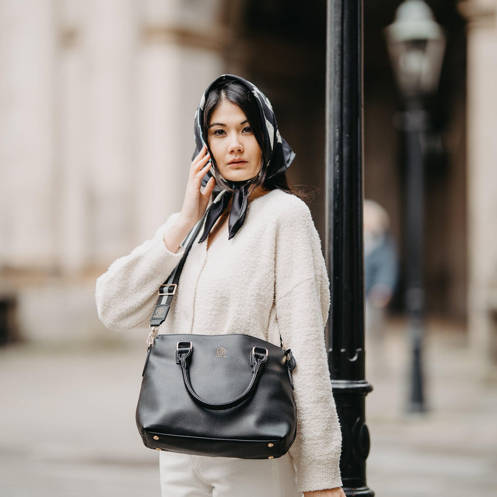 
                  
                    Eine junge Frau trägt ihre Grace in schwarz mit dem dazu passenden Gurt crossbody
                  
                