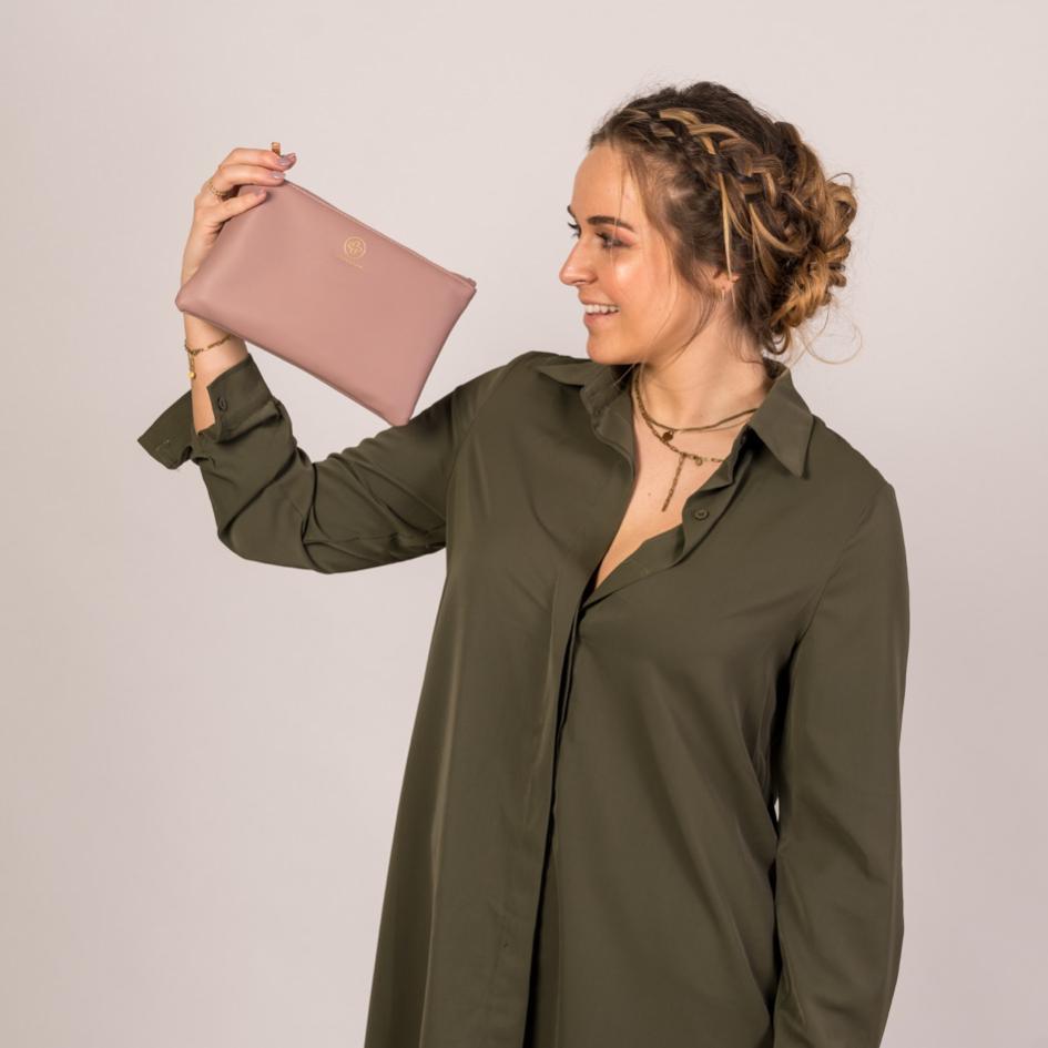 
                  
                    Die Mum Pouch in Puder wird in einer Hand in die Höhe gehalten
                  
                