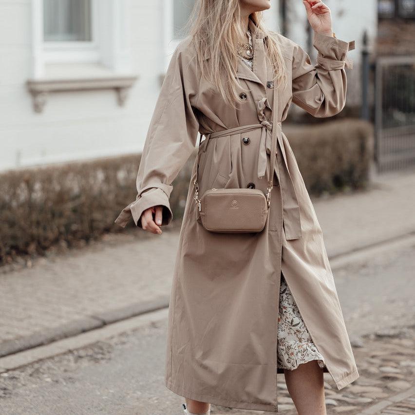 
                  
                    Die Jade in taupe wird zu einem Trenchcoat crossbody getragen
                  
                