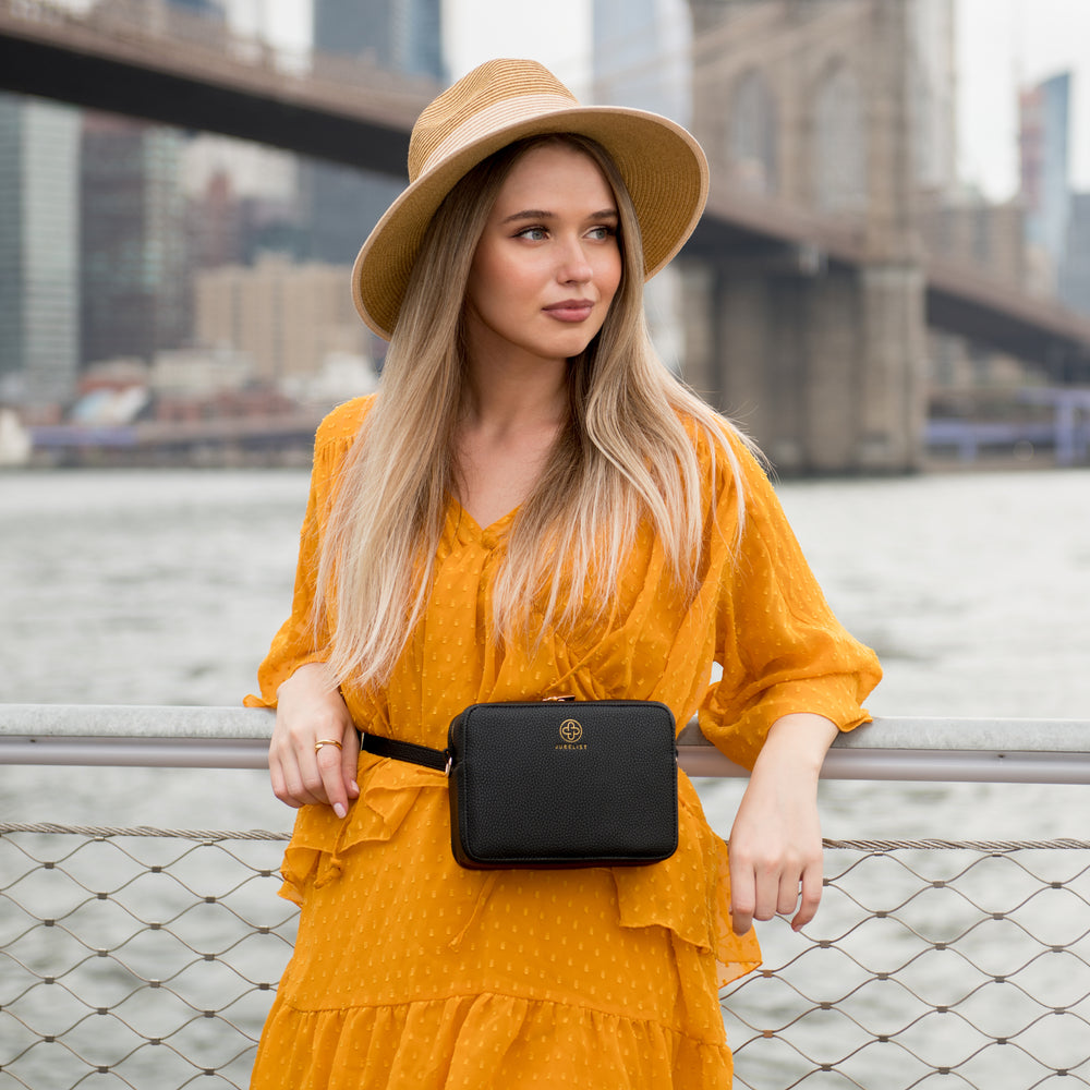 
                  
                    Eine junge Frau trägt zu einem gelben Kleid die Jade in schwarz als Bauchtasche
                  
                