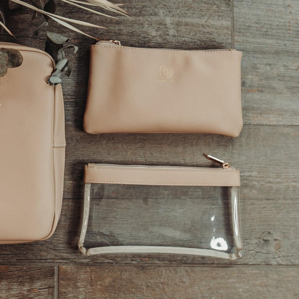 
                  
                    Das Pouch Set in sand liegt auf einem Holztisch und die Beauty Bag daneben
                  
                