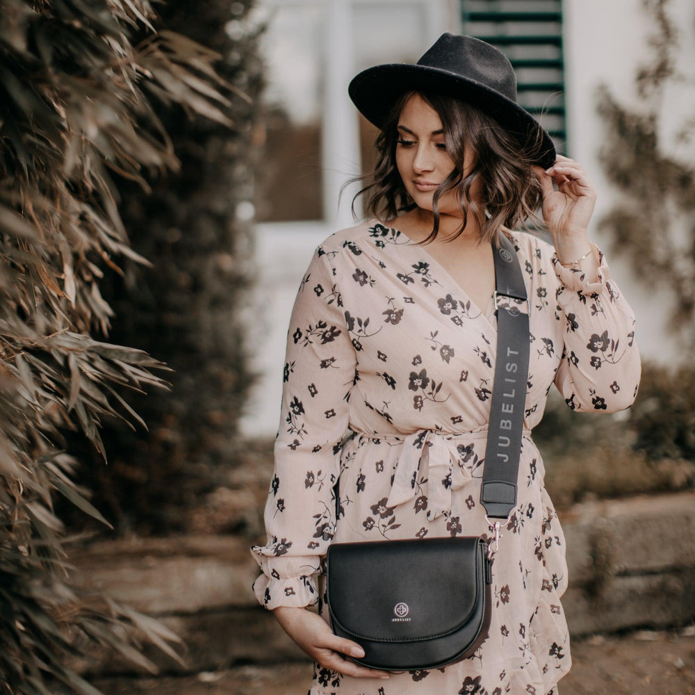 
                  
                    Eine junge Frau trägt crossbody den Fashion Strap schwarz silber an einer Saddle Bag in schwarz silber
                  
                